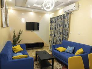 sala de estar con 2 sofás azules y TV en Maggie’s, en Dakar