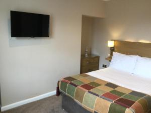 a hotel room with a bed and a flat screen tv at The Ramleh in Scarborough