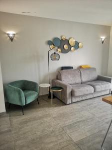 ein Wohnzimmer mit einem Sofa und einem Stuhl in der Unterkunft Appartement contemporain le Vendome à 90m de la plage in Le Grau-du-Roi