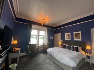 een slaapkamer met blauwe muren en een bed en een televisie bij Barriemore Oban in Oban