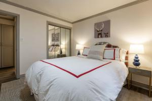 a bedroom with a large white bed with red stripes at Convenience and Style, Two Q Beds in Vail