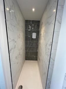 uma casa de banho com um chuveiro com azulejos pretos e brancos em 3 bedroom Garden apartment next to craig-y-don park em Llandudno