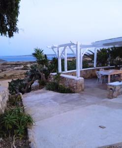een patio met een tafel en een witte pergola bij Afiartis Almira Cottage in Karpathos