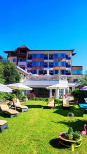 a hotel with lawn chairs and umbrellas in front of a building at Alpenhotel Stefanie - direkt buchbar in Mayrhofen