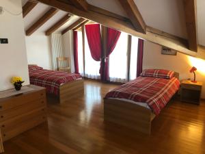2 camas num quarto com pisos e janelas em madeira em Casa Crepaz em Canale San Bovo