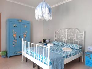 アグローポリにあるVilla Ada B&Bの青と白のベッドルーム(ベビーベッド、シャンデリア付)
