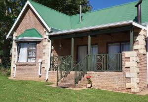 uma pequena casa de tijolos com um telhado verde em Clarens Mountain Sage Cottage em Clarens