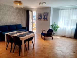 a living room with a table and a blue couch at Kolory Warmii Apartament Niebieski in Olsztyn