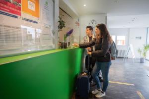 a man and a woman standing at a green counter at Nyon Hostel in Nyon