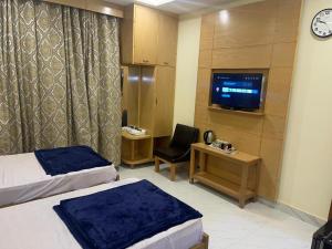 Mughal E Azam Hotel في Liāquatpur: غرفه فندقيه سريرين وتلفزيون