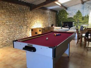 a pool table in a room with a stone wall at Les Gîtes de La Croix Liaud in Saint-Sulpice-en-Pareds
