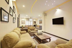 a living room with a couch and a tv on a wall at Tejdeep - A boutique 3BHK homestay in Jaipur