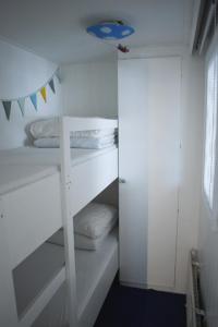 ein weißes Zimmer mit einem Etagenbett und einigen Kissen in der Unterkunft Luxe gezellig chalet aan het water Friesland. in Suameer