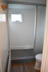 ein Bad mit Dusche, WC und Fenster in der Unterkunft Luxe gezellig chalet aan het water Friesland. in Suameer