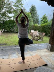 een vrouw die een yoga pose doet op een mat bij El Jardin de las Magnolias Hotel in Quintana de Soba