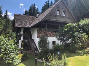 a house with a wooden roof and stairs in a yard at Charmantes Bauernhaus in erhöhter Aussichtslage in Modriach