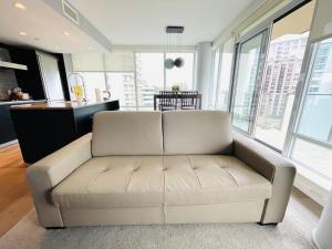 a white couch in a living room with windows at Deluxe 2 bedroom suite downtown free parking with pool and Air Conditioning in Victoria