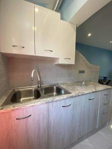 eine Küche mit einem Waschbecken und weißen Schränken in der Unterkunft Corfu Sunset apartment in Liapades