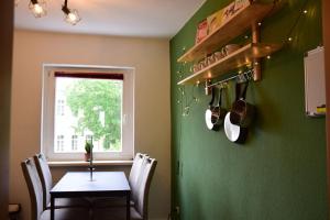 eine Küche mit einem Tisch und einer grünen Wand in der Unterkunft Haus mit 3 Apartments im Zentrum von Rostock in Rostock
