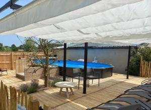 a large white umbrella on a deck with a swimming pool at Op 't Roth 12 ruime sfeervolle vakantiewoning in 't groen in Oudenaarde