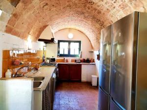 cocina con techo de ladrillo y cocina con electrodomésticos de acero inoxidable en Masía para grupos con piscina privada28 pax, en Girona