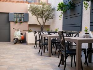 un patio avec des tables et des chaises et un scooter en arrière-plan dans l'établissement Domo Anna, à Villasimius