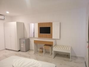 Habitación blanca con escritorio y TV en la pared. en Hotel Neptunia Skanes en Monastir