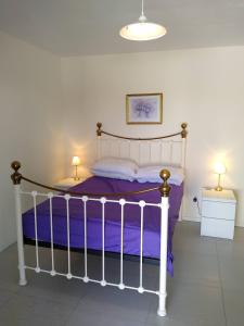 1 dormitorio con 1 cama con sábanas moradas y 2 lámparas en Poppey, en Péret