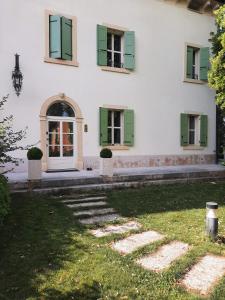 una casa bianca con persiane verdi e una porta di Montresora, villa con piscina privata tra il Lago di Garda e Verona a Sona