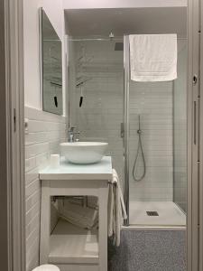 uma casa de banho branca com um lavatório e um chuveiro em La casa di Nonna Rosa em Sant'Agnello