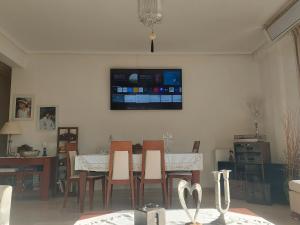 een eetkamer met een tafel en een tv aan de muur bij AIGIO PARK APARTMENT in Aigio