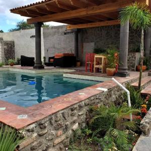 einen Pool in einem Garten mit einer Steinmauer in der Unterkunft Casa Saltito in San Miguel de Allende