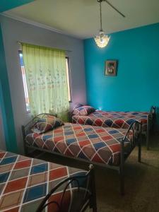 a bedroom with two beds and a blue wall at Hotel Eloy Alfaro in Guayaquil