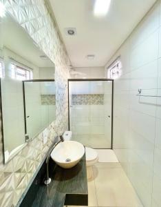 uma casa de banho com um lavatório, um chuveiro e um WC. em Hotel Armenia em Cascavel