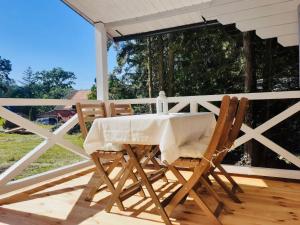 una mesa y sillas en un porche con una valla blanca en Domki w Lesie en Silnowo