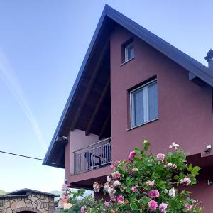 een roze gebouw met een balkon en bloemen bij Villa Pjene in Konjic