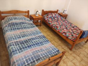 two twin beds in a room with two tables at Blue and White Apartments in Benitses