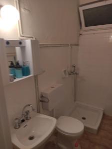 a white bathroom with a toilet and a sink at Blue and White Apartments in Benitses