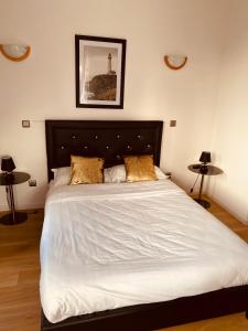 een slaapkamer met een bed met witte lakens en gouden kussens bij Home SAINT MICHEL-restaurant Chicken cabana in Pontorson