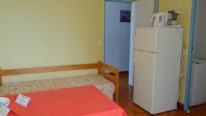 サゴーヌにあるResidence Funtanellaの白い冷蔵庫とテーブルが備わる小さな客室です。