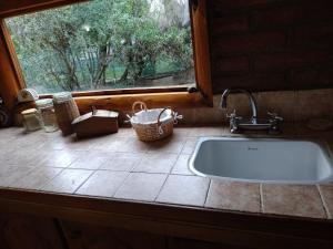 a kitchen sink with a window and a basket on the counter at Maitenkarú in San Carlos de Bariloche +23 photos