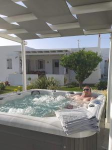 a man sitting in a jacuzzi tub in a backyard at GeoNi's villa & garden spa in Apollonia