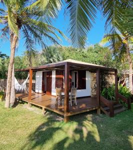 a cabin with a deck on the grass with a palm tree at Casa Della in Luis Correia