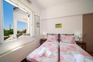 two beds in a room with a window at Villa Erasmia- House 1 ground floor in Sarláta +41 photos