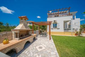 a stone patio with a brick fireplace in front of a house at Villa Erasmia- House 1 ground floor in Sarláta