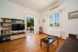 a living room with a couch and a tv at Villa Erasmia- House 1 ground floor in Sarláta