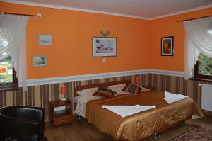 a bedroom with a bed with an orange wall at Hotel Restauracja Redos in Nysa