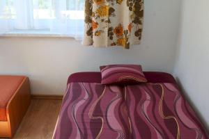 Cama morada en habitación con ventana en Siódemka w Dziwnówku, en Dziwnówek