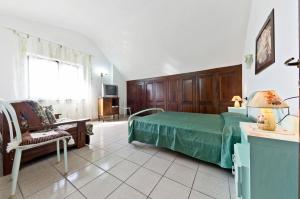 a bedroom with a green bed and a chair at Appartamenti Poggio Rineschi in Montenero