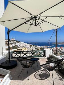 a patio with a table and an umbrella at Elia Concept Apartments in Ano Syros